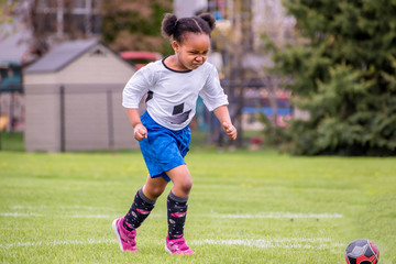 A young girl is learning how to play soccer	