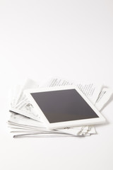 digital tablet with blank screen on pile of newspapers, on white