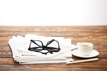 eyesight, cup of coffee, digital tablet and pile of newspapers on wooden surface