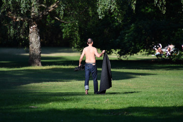 Fototapeta premium A man carries his blanket in a park in Berlin-Germany on a warm and sunny spring day
