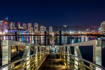 skyline of downtown Vancouver at night with mountains in background