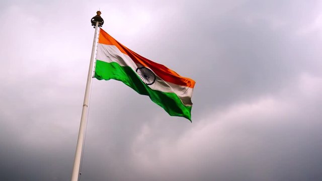 Indian tricolor flag fluttering in the wind shot against a dark cloudy sky on a beautiful rainy stormy evening. The huge flag showcases the patriotism of the indian superpower