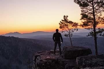 A man stands on the edge of a rock