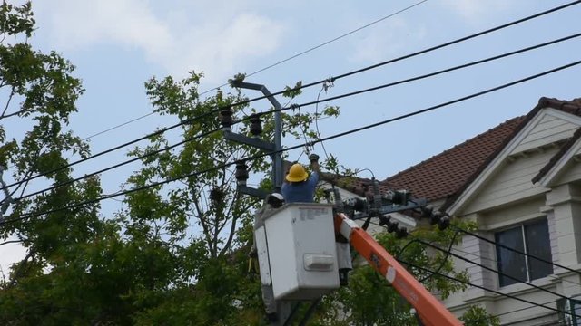 Electrician worker of Metropolitan Electricity Authority work repair electrical system on electricity pillar or Utility pole on April 21, 2018 in Nonthaburi, Thailand