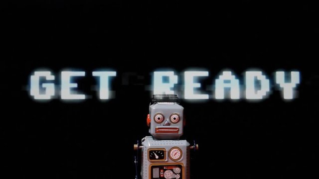 A neurotic tin toy robot walking over a background of text appearing with digital glitch: player one, get ready, go!
