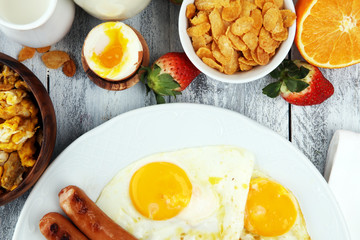 Traditional full English breakfast with fried eggs, sausages, beans, mushroomsand bacon on wooden background