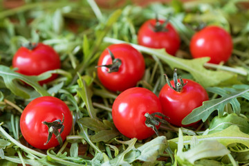 fresh, red cherry tomatoes on green arugula background