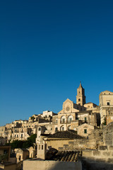 Obraz premium Vertical View of the City of Matera at Sunset on Clear Blue Sky Background