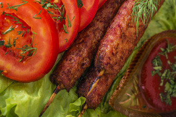 lulia kebab on a salad with tomatoes and dill