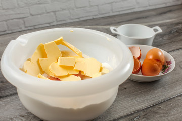 White plastic bowl with butter, egg yolk, flour and salt, ready to be mixed - preparation for baking a cake.