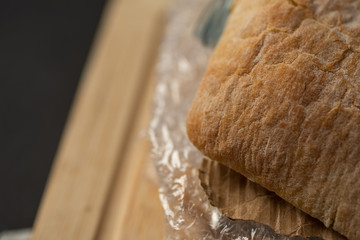 Fresh tasty panini sandwich with plastic waste and paper cardboard inside on wooden board. Recycled waste in our food concept