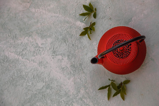 Red cast iron tea pot on gray concrete background, top view, copy space