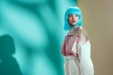 portrait of beautiful stylish young woman in blue wig looking away in studio