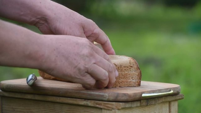 Men's hands cut bread on the Board in nature