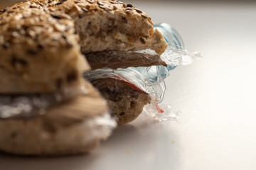 Fresh tasty cut out burger panini with plastic waste and paper cardboard inside on white background. Recycled waste in our food concept