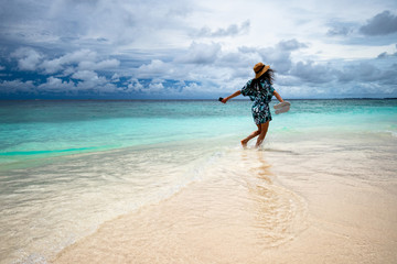 happy girl runs barefoot along the ocean shore