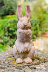 Close-up of a terracotta rabbit resting on a wall. Selective focus and blurred background.