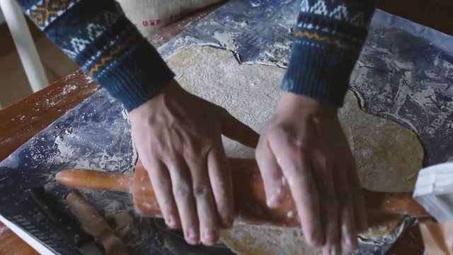 male hands rolling dough with pin at home, pastry cooking, preparation of pizza, pie or cookies