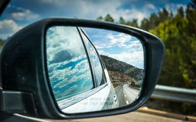 Fototapeta premium View of the highway in the side mirror of the car. Summer Car Tour in the USA