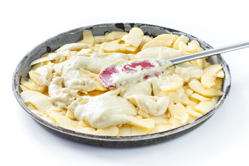 Preparation of an apple pie, spreading the dough on the apples. White background