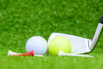 Close up golf ball, golf clubs driver and tee on green grass field background.
