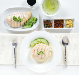 Hainanese chicken rice with cucumber on dish and hainanese chicken on plate with sauce isolated, square top view.
