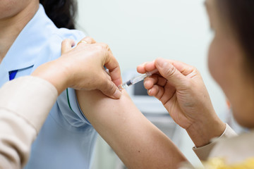 Close up doctor's hand injecting for vaccination in the shoulder woman patient.Vaccine for protection concept.