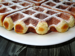 Belgian waffles in a white plate on wooden table. Homemade dessert	