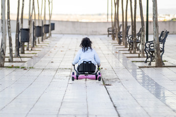 Obraz premium Hoverboard o patín eléctrico con sillín manejado por una niña morena rizosa mientras juega en el barrio