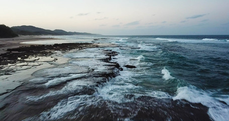 Aerial of waves crashing on reef at sunset