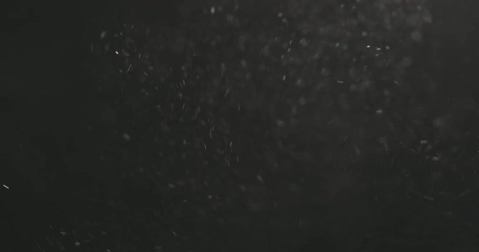 Slow motion dust particles explosive wave over black background