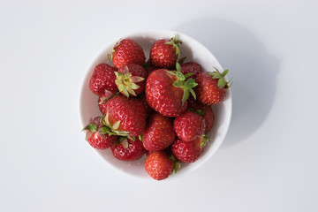 Bowl with fresh strawberries on white, top view.