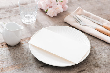 Spring table decoration with flowers. White plates, fork, knife on wooden plate
