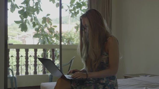 Woman working on laptop in the hotel during vacation. Freelance job concept.