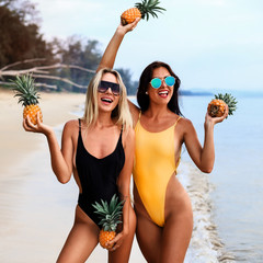 two incredibly beautiful sexy girl models in a bikini on the sea shore of a tropical island, blonde brunette, bronze tan, travel summer vacation, fashion style