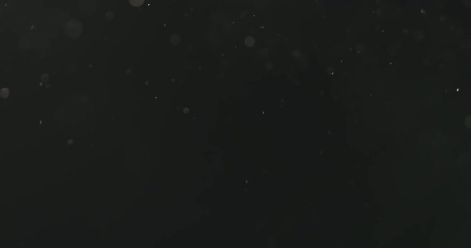 Slow motion dust particles floating over black background