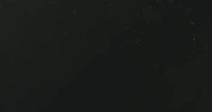 Slow motion dust particles floating over black background