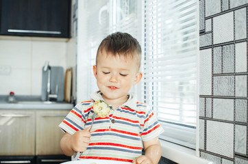 the child in the kitchen with a fork eating young potatoes