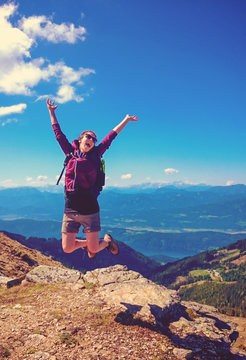 happy woman jumping on top of a mountain