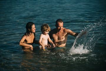 Happy family at a sea having fun and splashing water in summer.