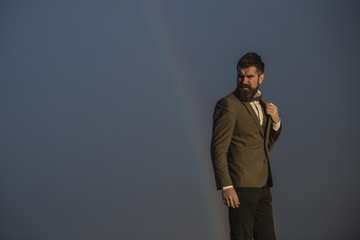 Bearded man gay and rainbow. Hipster with beard and mustache on grey sky. Fashion businessman in...