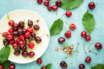 organic cherries in a dish and scattered on rustic wooden background. Top view