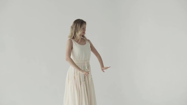 attractive girl is dancing in a white dress on a light background.