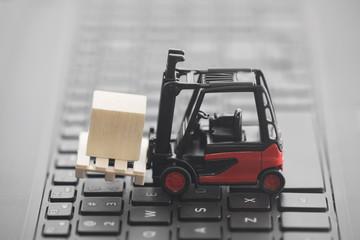 Forklift miniature with wooden block on laptop keyboard