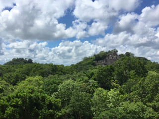 Ancient Maya ruin in Calakmul, Campeche, Mexico rising out of the jungle set against a cloudy sky