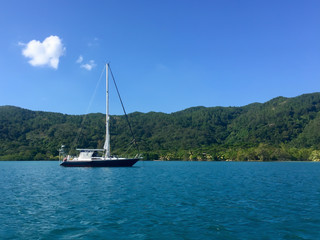 Sail boat on the calm caribbean waters of Guanaja, Honduras with jungle mountains in the background