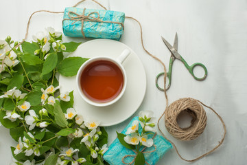 Flowers and gifts and a cup of tea on a light background. It is possible to use both for inscription, demonstration of fonts, and as a postcard