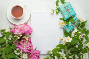 Empty frame with flowers and gifts and a cup of tea on a light background. It is possible to use both for inscription, demonstration of fonts, and as a postcard