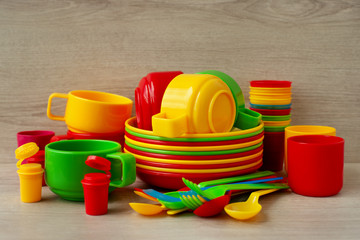 A set of plastic utensils. Dishes made of colorful plastic for picnic or camping. A set of plates, mugs and cutlery for eating in nature.