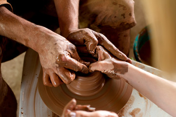 Mid-section of girls making pot in pottery workshop